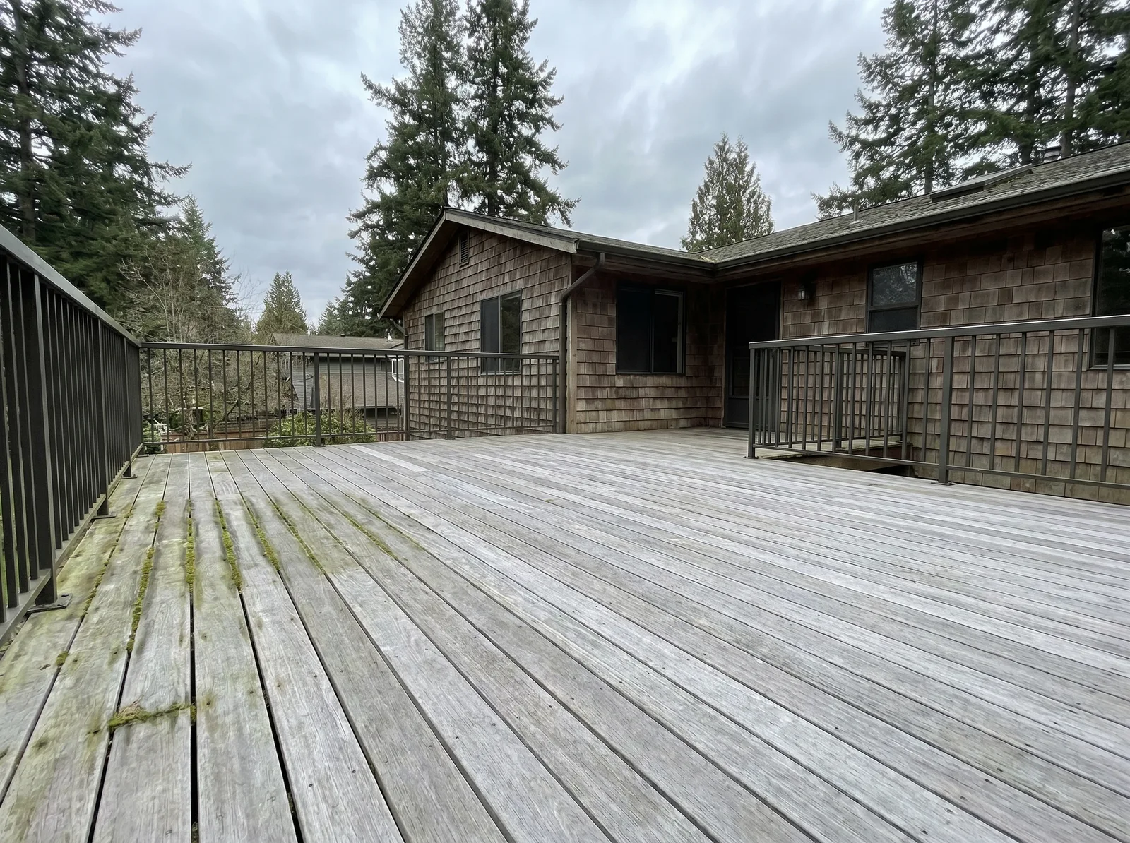 Weathered grey Ipe deck with moss in the board gaps before refurbishment in Bellingham
