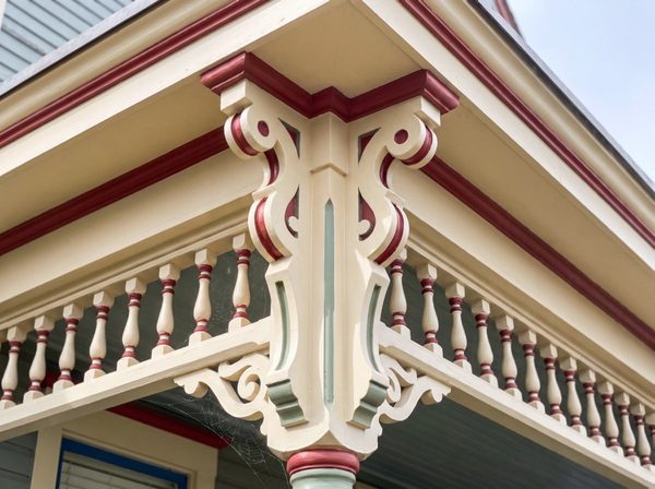 Same porch bracket after scraping, priming and repainting in cream with red accents