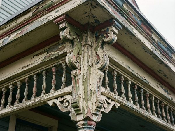 Peeling paint on a carved Victorian porch bracket before repainting